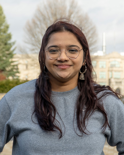 A student standing and smiling outside