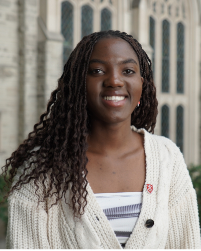 A student with black hair smiling with stone architecture in the background
