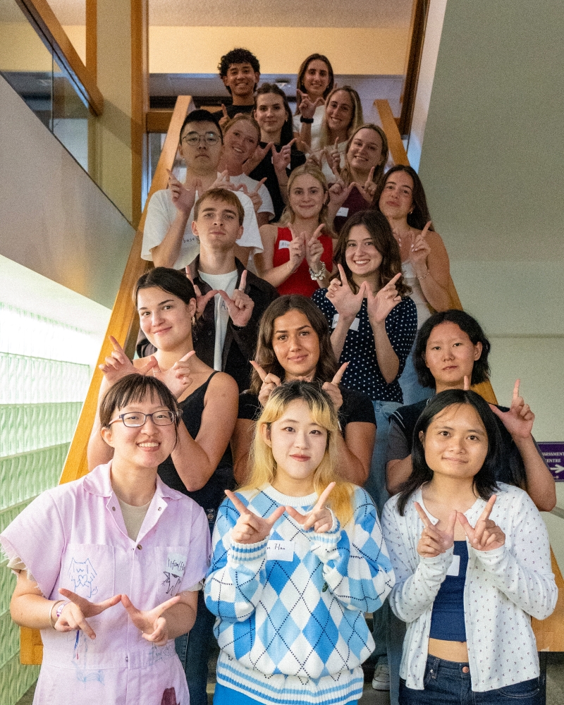 group of students smiling and giving Western "Ws" on the stairs