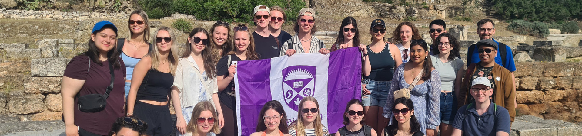Students standing and smiling holding a Western U flag