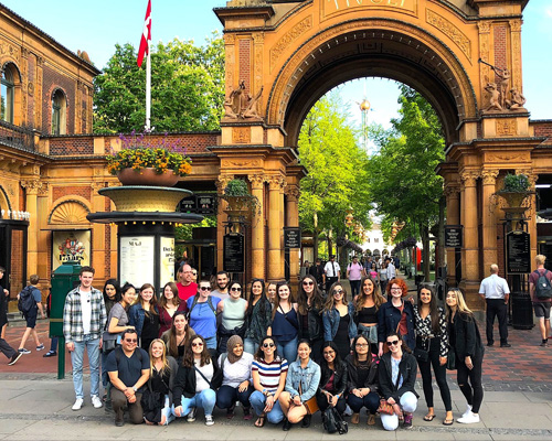 Students standing in front of a gothic arch