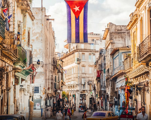 bright, vibrant street in Cuba. Cuban Flag hanging front and center.
