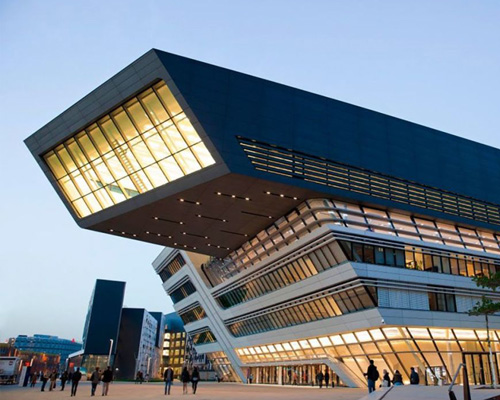 Modern-style building in Vienna. Building looks like it's leaning over the street. People walking in the distance on the street.