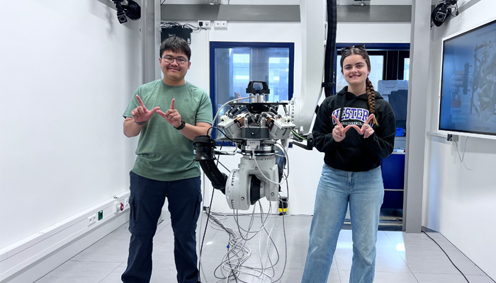 Students standing in front of technology and giving the Western W