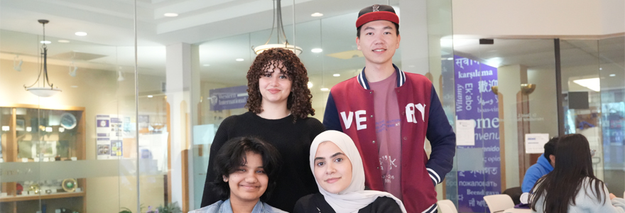 Group of students sitting in front of a table and smiling